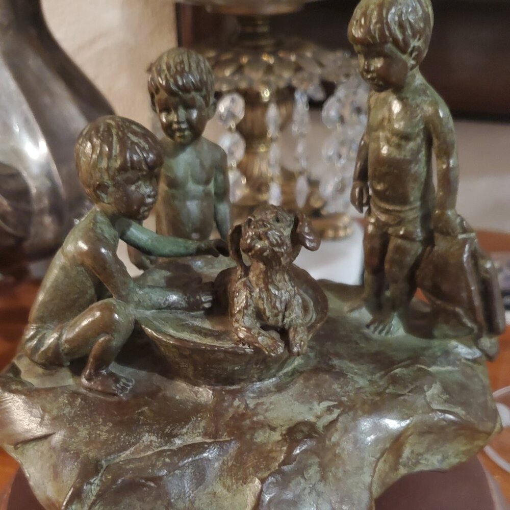 vintage or antique bronze sculpture featuring three kids playing with dog